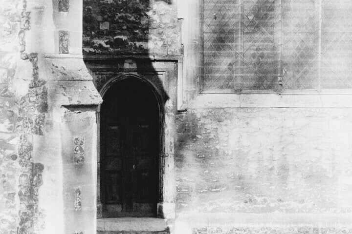 A black and white photo of a church door.