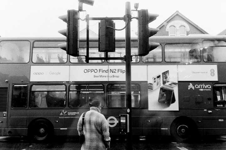 Shot through a window of someone waiting to cross the road while a bus goes past.